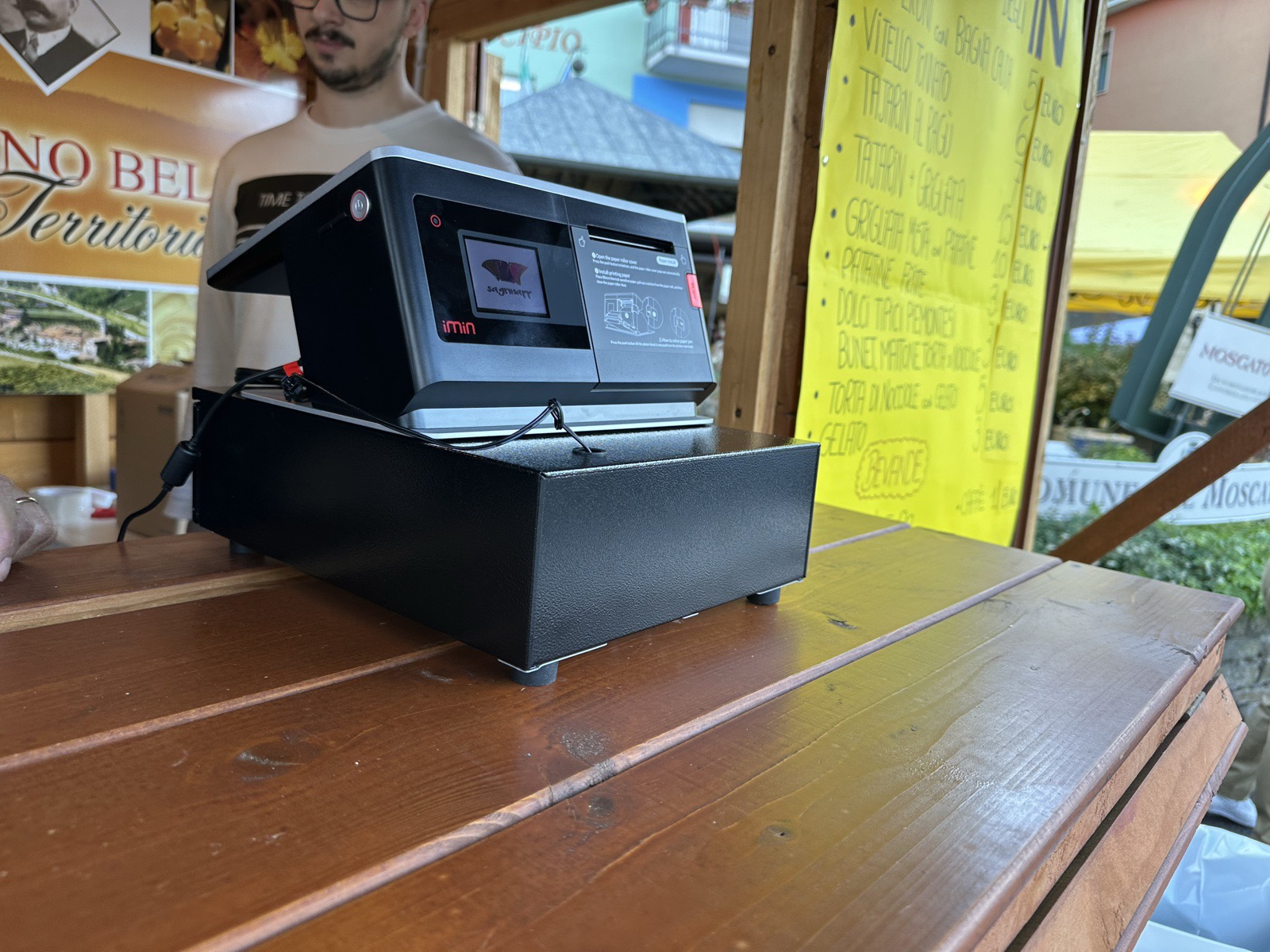 Il dispositivo Sagrinapp in cassa a una sagra Pro Loco, con il menu cartaceo accanto